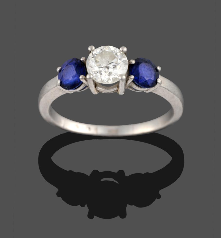 Lot 238 - A Diamond and Sapphire Three Stone Ring, a round brilliant cut diamond between two round cut...