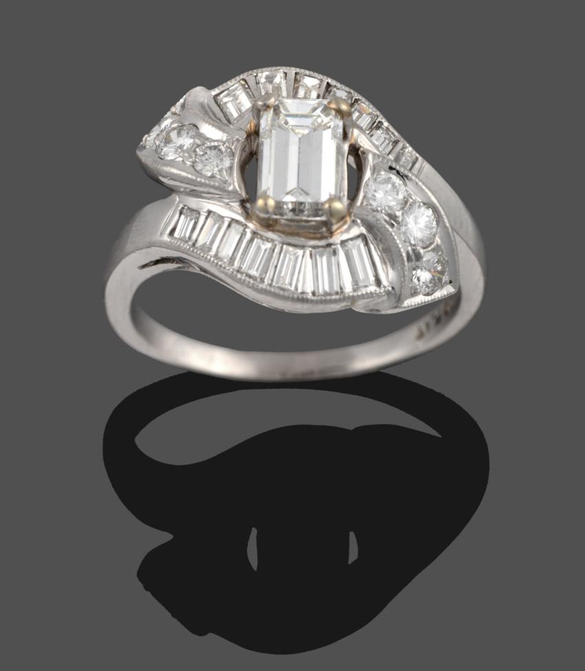Lot 245 - A Diamond Cluster Ring, an emerald-cut diamond within a four claw setting, to twist shoulders inset