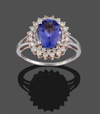 Lot 328 - An 18 Carat White Gold Tanzanite and Diamond Ring, the oval cut tanzanite within a border of...