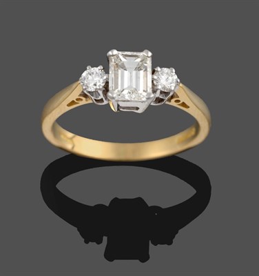 Lot 347 - An 18 Carat Gold Diamond Three Stone Ring, an emerald-cut diamond sits between two round...