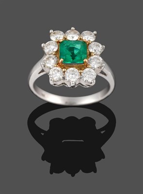 Lot 370 - An Emerald and Diamond Cluster Ring, the square trap cut emerald in a yellow claw setting, within a