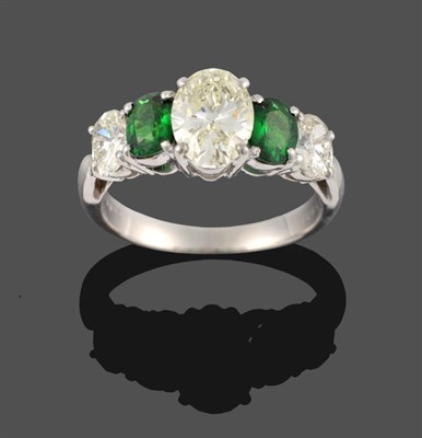 Lot 371 - A Diamond and Green Stone Five Stone Ring, three graduated oval cut diamonds alternate with two...