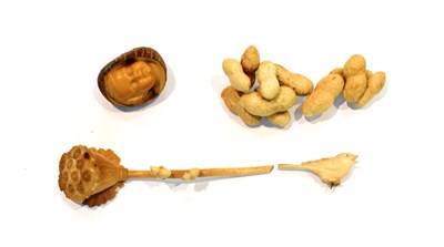 Lot 261 - A tagua nut, carved with a child's face, 4.5cm long; a carving of a bird, on a seed head, 12cm...