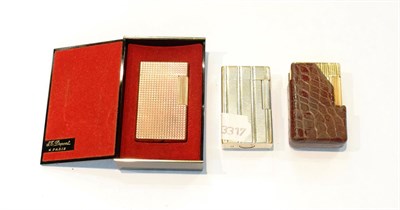 Lot 292 - A white metal S.T. Dupont cigarette lighter No. 19HHK70, a gilt metal S.T. Dupont cigarette lighter