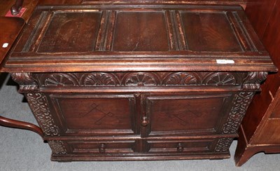 Lot 1367 - A reproduction carved oak chest with hinged lid, cupboard doors and two drawers, 106cm wide