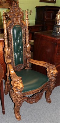 Lot 1393 - A reproduction carved hardwood armchair covered in green leather, 74cm wide