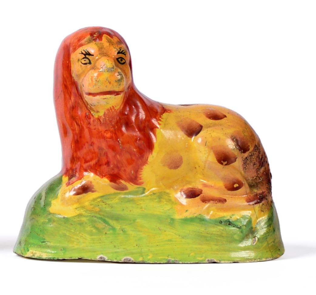 Lot 4 - A Staffordshire Yellow Glazed Pottery Figure of a Lion, early 19th century, the recumbent...