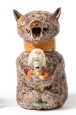 Lot 20 - A Pratt Type Bear Jug and Cover, circa 1800, the seated beast clutching a caricature of...