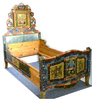 Lot 491 - A Painted Pine Bedframe, the raised headboard centred with a religious scene between scrolling...