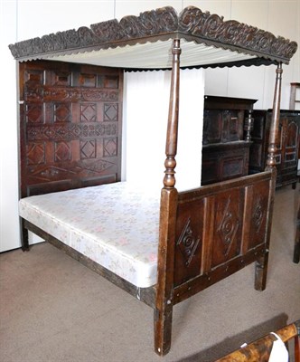 Lot 561 - A Joined Oak Tester Bed, with leaf carved undulating cornice and cloth lined tester, a panelled...