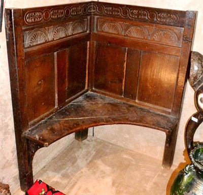 Lot 702 - A Small Joined Oak Corner Settle, with carved top rail and lunette carved frieze, curved board...