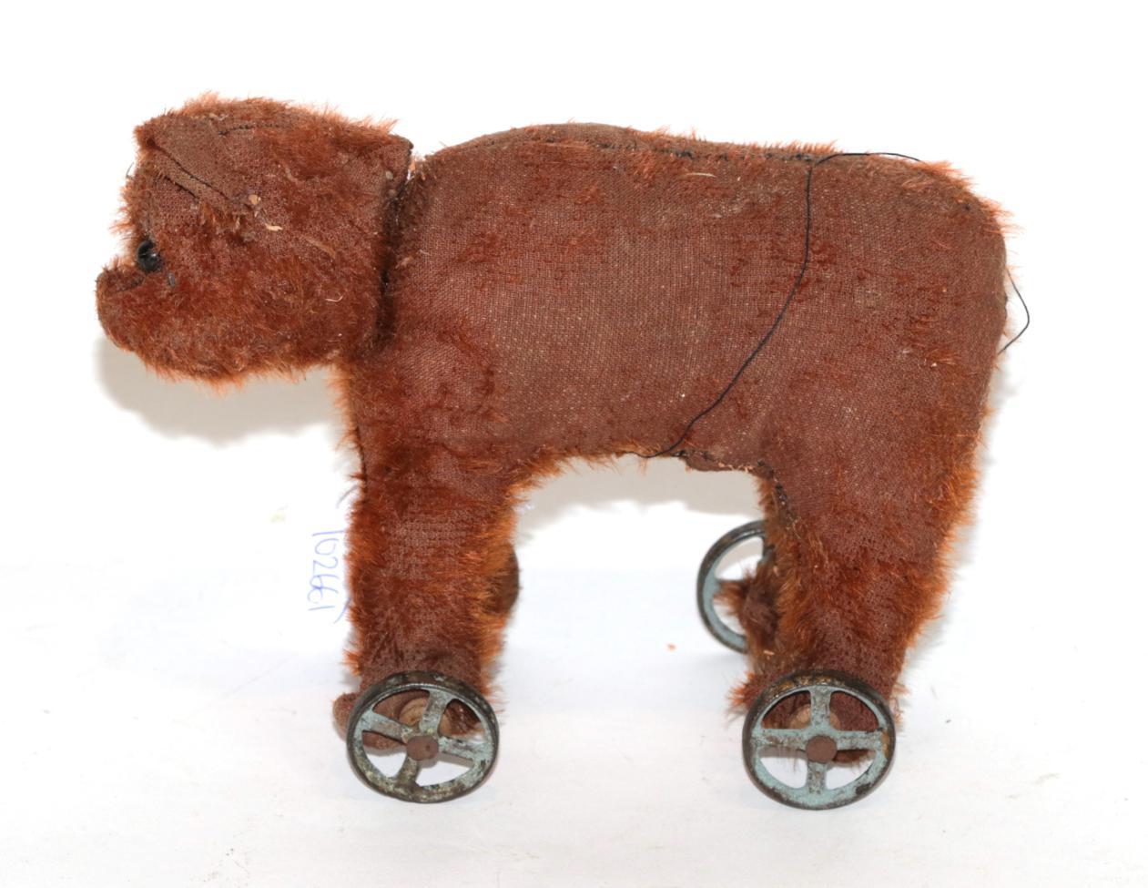 Lot 1022 - An early 20th century Steiff bear on wheels in red/brown mohair, boot button eyes, on four...
