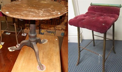 Lot 1222 - An 18th century oak circular tilt top tripod table and a brass stool with red button seat