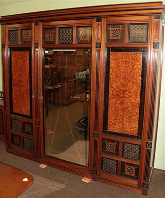 Lot 1289 - An Aesthetic movement walnut, ebonised and burr triple door mirrored wardrobe, the stepped...