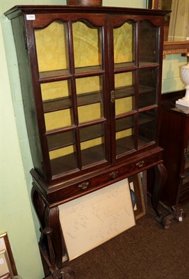 Lot 1309 - An oak glazed cabinet on stand, with two doors enclosing adjustable shelves, raised on a stand with