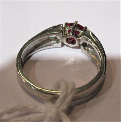 Lot 51 - A ruby type and diamond ring, an oval cut ruby type in a white claw setting, flanked by...