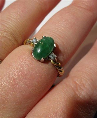 Lot 55 - An 18 carat two colour gold jade and diamond ring, the central cabochon jade flanked by two...