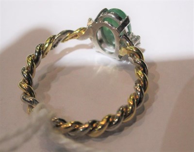 Lot 55 - An 18 carat two colour gold jade and diamond ring, the central cabochon jade flanked by two...