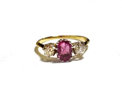Lot 71 - A ruby and diamond ring, an oval mixed cut ruby flanked by two old cut diamonds in white claw...