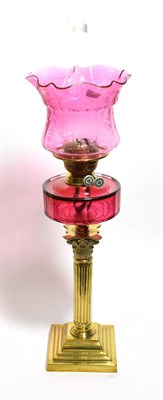 Lot 164 - A Victorian oil lamp with a brass Corinthian column base and cranberry tinted shade