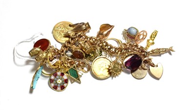 Lot 348 - A charm bracelet hung with various charms including a 1908 sovereign, an articulated fish, a swivel