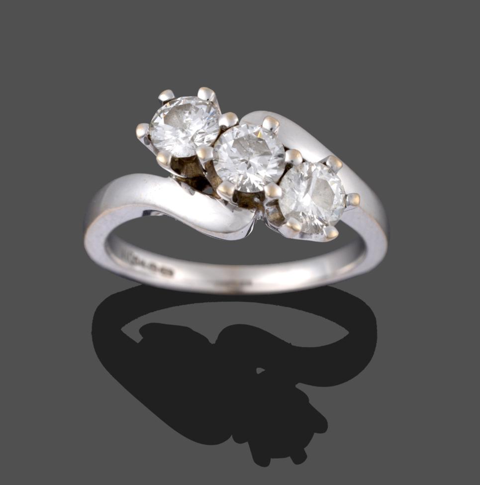 Lot 2006 - An 18 Carat White Gold Diamond Three Stone Twist Ring, the round brilliant cut diamonds in claw...