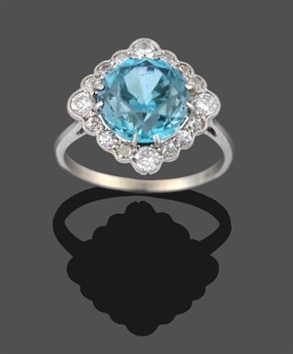 Lot 2022 - A Blue Zircon and Diamond Cluster Ring, the round cut blue zircon in white claw settings,...