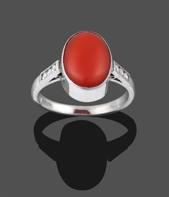 Lot 2025 - An 18 Carat White Gold Coral and Diamond Ring, the oval cabochon coral in a white collet setting to
