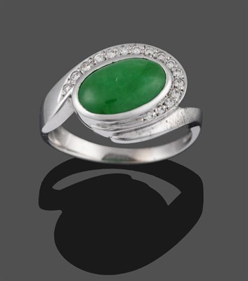 Lot 2028 - An 18 Carat White Gold Jade and Diamond Ring, an oval cabochon jade in a collet setting with a...