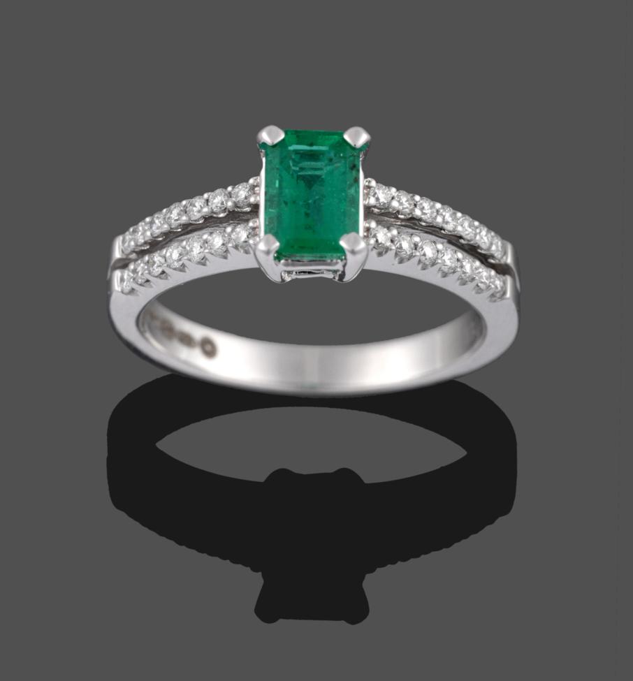Lot 2034 - An 18 Carat White Gold Emerald and Diamond Ring, the emerald-cut emerald in a four claw setting, to