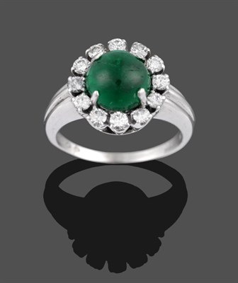 Lot 2036 - An Emerald and Diamond Cluster Ring, the cabochon emerald within a border of twelve round brilliant