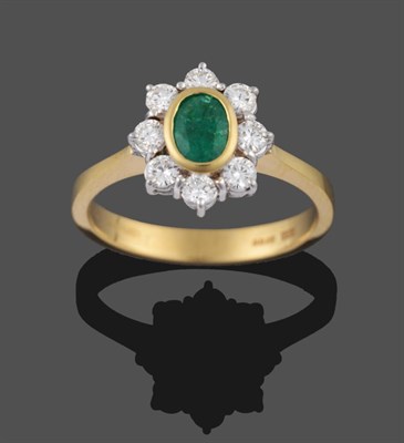 Lot 2039 - An 18 Carat Gold Emerald and Diamond Cluster Ring, the oval cut emerald in a yellow collet...
