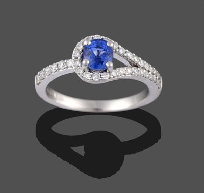 Lot 2057 - An 18 Carat White Gold Sapphire and Diamond Ring, the oval cut sapphire in a looped frame,...