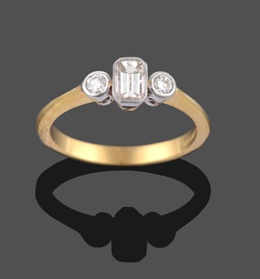 Lot 2092 - An 18 Carat Gold Diamond Three Stone Ring, an emerald-cut diamond sits between two round...