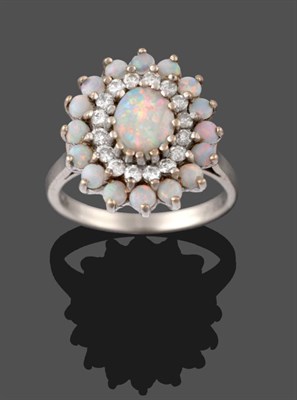 Lot 2120 - An 18 Carat White Gold Opal and Diamond Cluster Ring, an oval cabochon opal within a border of...