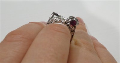 Lot 2137 - An Art Deco Style Ruby and Diamond Ring, the geometric and scroll form set with baguette cut,...