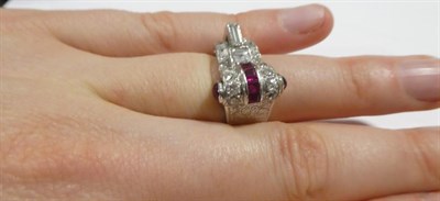 Lot 2137 - An Art Deco Style Ruby and Diamond Ring, the geometric and scroll form set with baguette cut,...
