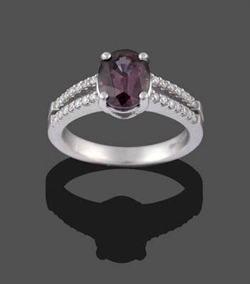 Lot 2144 - A Platinum Garnet and Diamond Ring, the oval mixed cut garnet in four claws, to tramline...