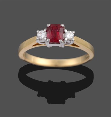 Lot 2189 - An 18 Carat Gold Ruby and Diamond Three Stone Ring, the modified emerald-cut ruby sits between...