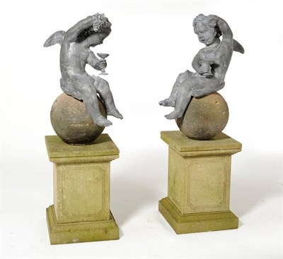 Lot 1015 - A Charming Pair of Winged Lead Putti Seated Upon Artificial Stone Spheres, After the 18th...