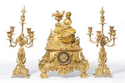 Lot 1046 - A French Gilt Metal Striking Mantel Clock with Garniture, circa 1850, the case surmounted by a lady