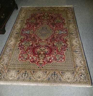 Lot 1115 - Ghom Rug Central Persia The burgundy field with urns issuing flowers around a cusped medallion...