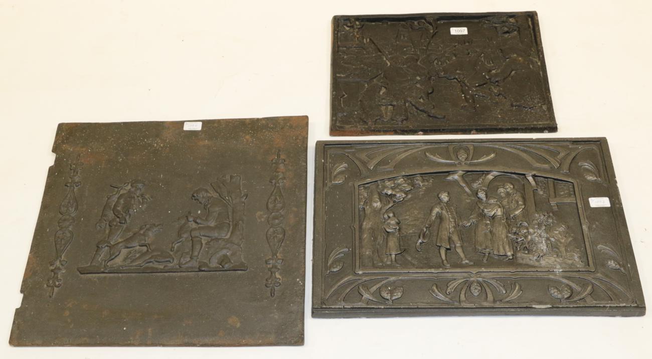 Lot 1097 - Three cast metal firebacks, one example depicting figures outside a house, 60cm by 39cm;...