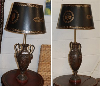 Lot 1122 - A pair of patinated metal Classical style table lamps with simulated toleware shades