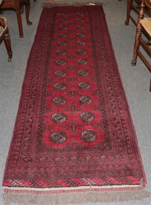 Lot 1195 - Narrow Afghan runner, the claret field with two columns of guls enclosed by multiple narrow...