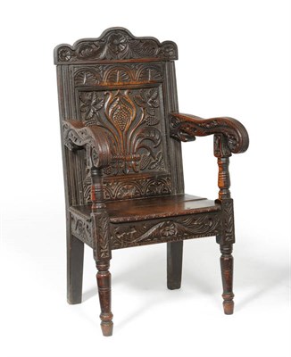 Lot 1156 - A Joined Oak Armchair, the profusely carved top rail and fielded panel back between lunette...