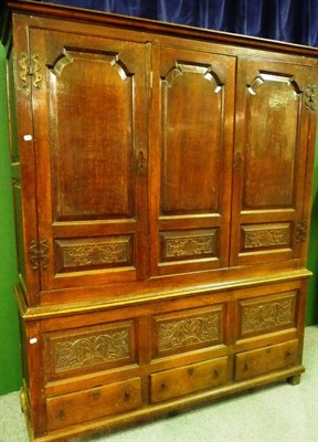 Lot 1161 - A Joined Oak Press Cupboard, with three fielded panel doors above six relief carved panels and...