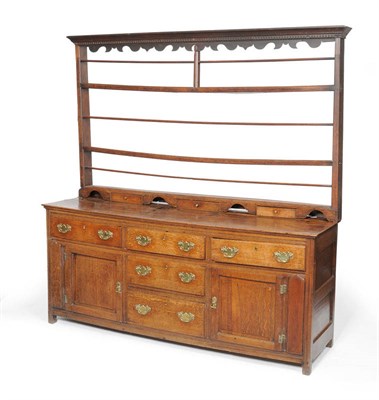 Lot 1166 - A Mid 18th Century Joined Oak Enclosed Dresser Base and Rack, the dentil and wavy shaped frieze...