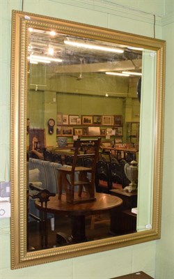 Lot 425 - A reproduction gilt bevelled glass mirror, 137cm by 106cm