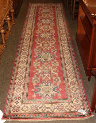 Lot 449 - A narrow Afghan runner of Caucasian design, the strawberry field with a column of Lesghi guls,...